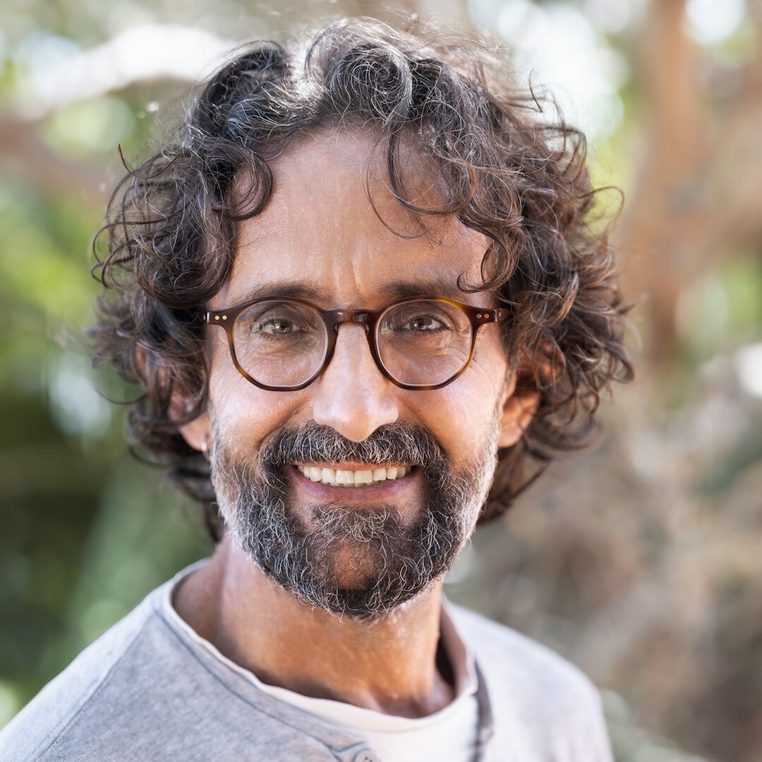Studio portrait of a smiling Brazilian man with glasses