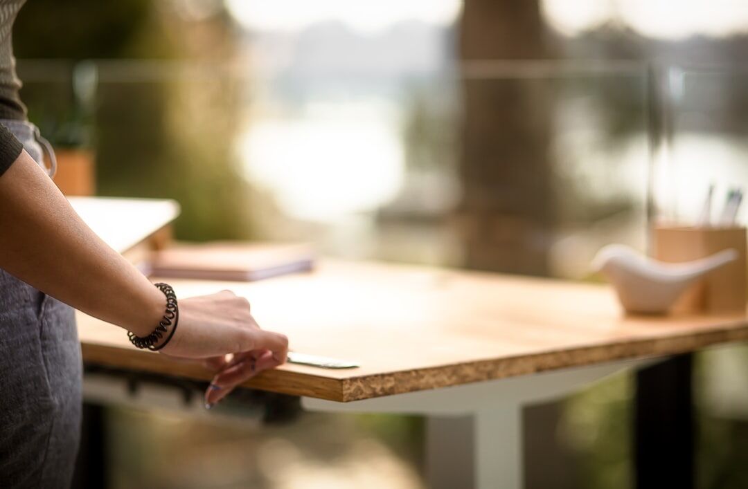 Brazilian woman writing in a journal at a wooden desk near a window
